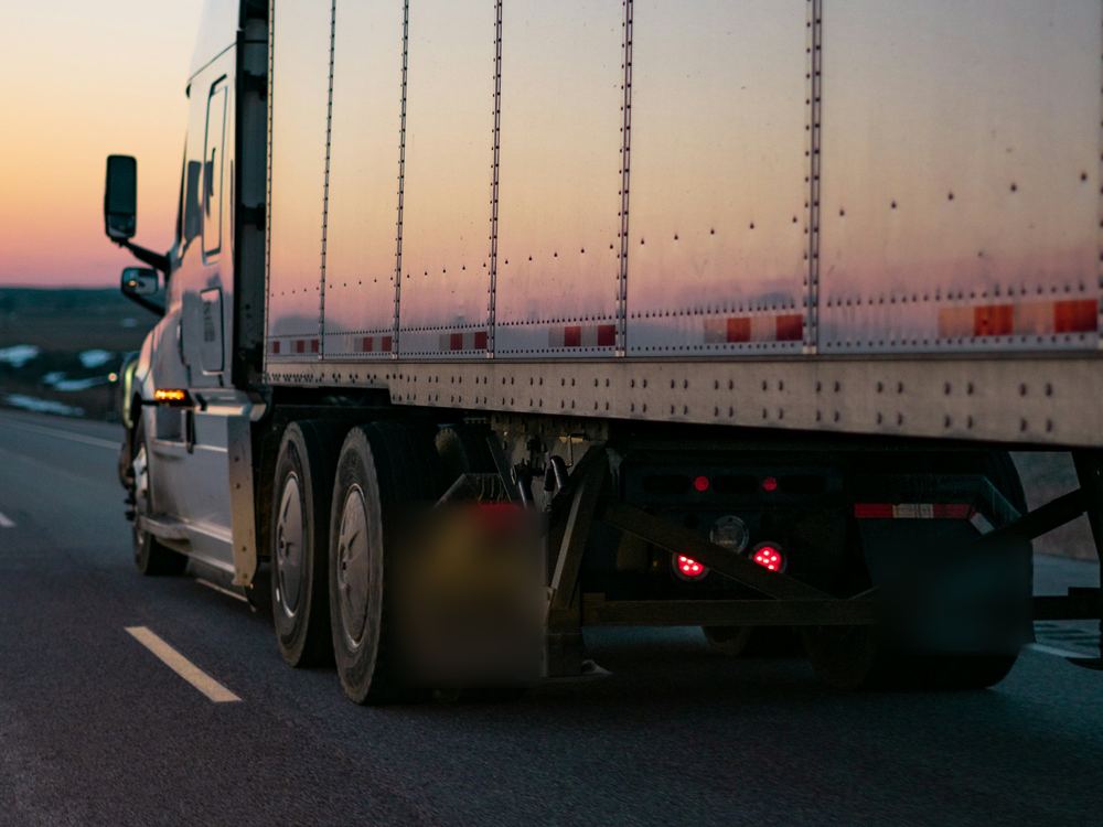 Tractor-trailer with a 53-foot dry van on the highway at dusk